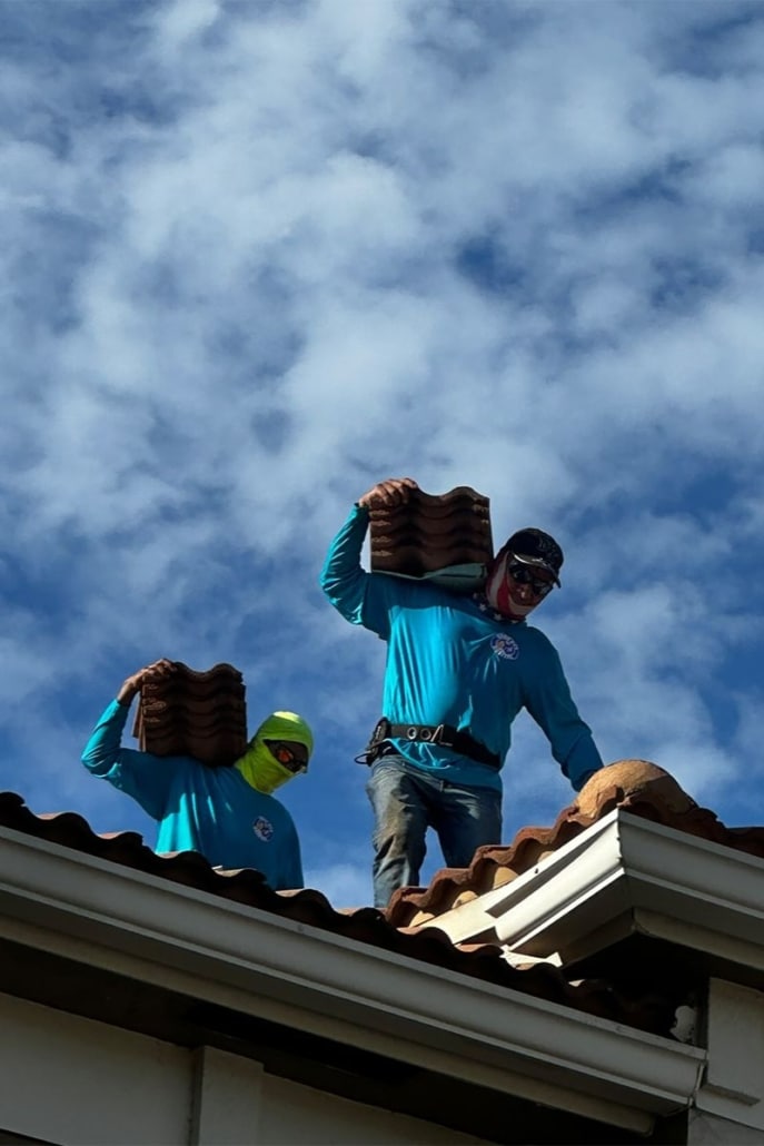 Roofing contractors installing tile roofing on a South Florida home under clear skies