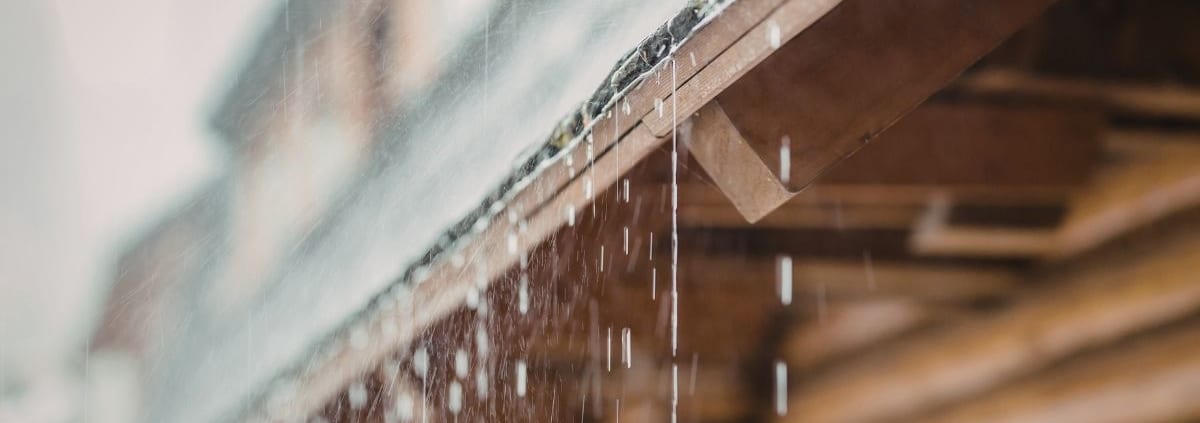 Detailed view of a blue-gloved hand placing a single grey square paver stone into position within a larger paved area.