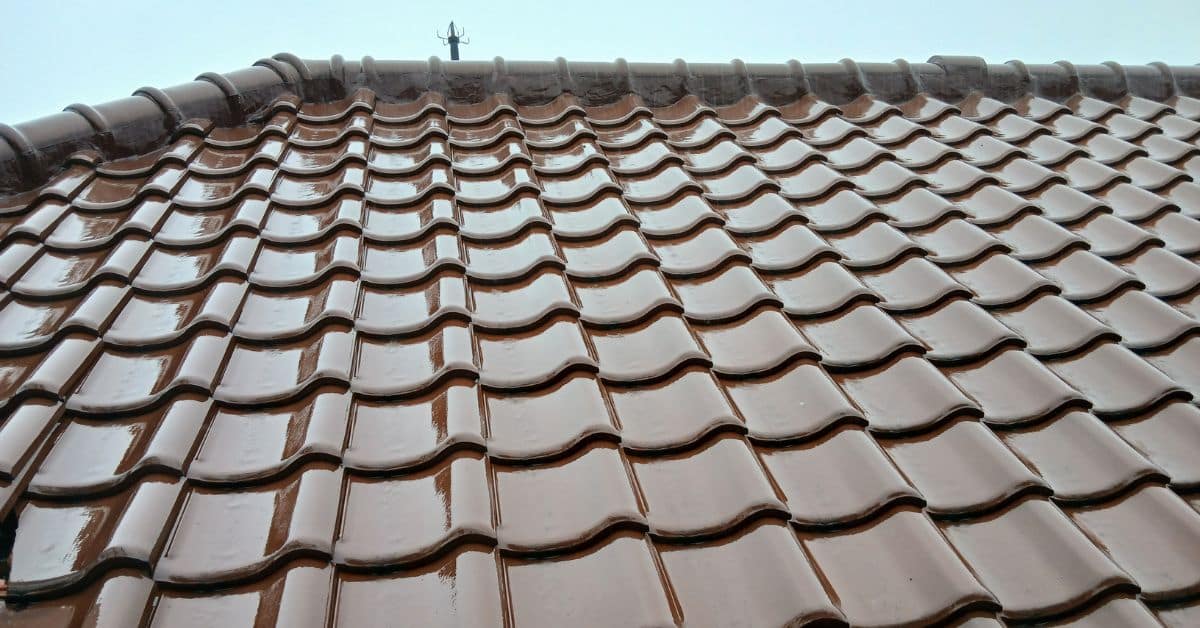 Rainwater dripping from the edge of a residential roof during a storm, highlighting potential water runoff issues.