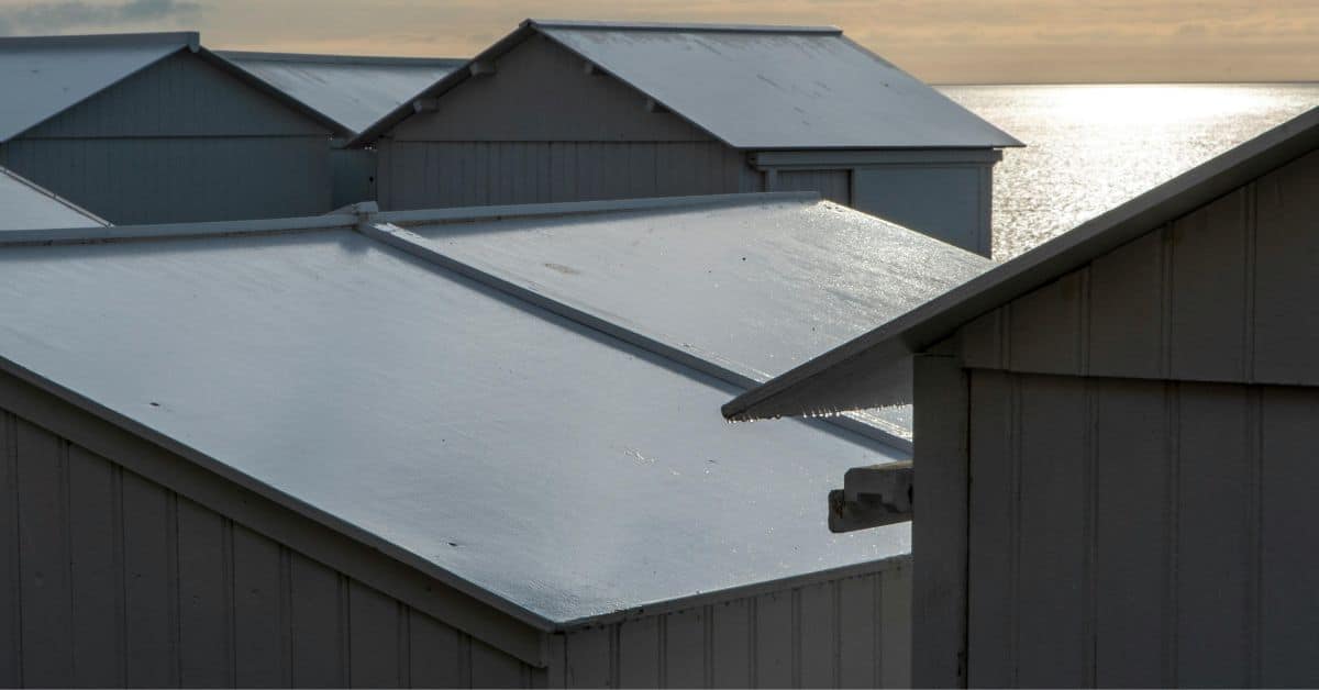 Close-up of multiple white metal roof sections overlapping at the ridges to provide a weather-proof seal on a seaside structure.