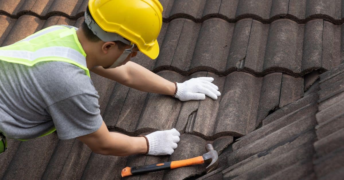 A wide view of a residential roof mid-replacement, showing exposed yellow wooden decking being covered with black waterproof synthetic underlayment.