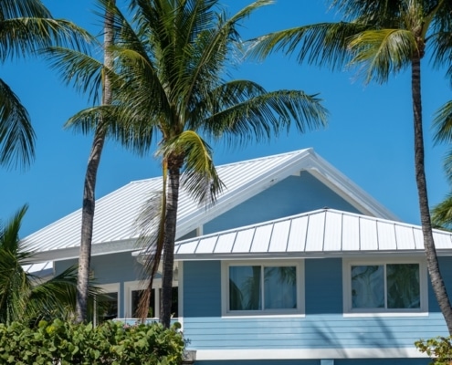 Light blue South Florida home with a white metal roof designed to withstand tropical weather and hurricane conditions.