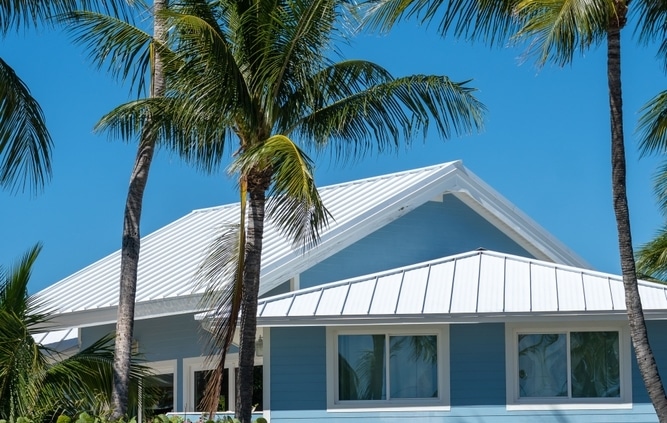 Light blue South Florida home with a white metal roof designed to withstand tropical weather and hurricane conditions.