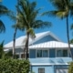 Light blue South Florida home with a white metal roof designed to withstand tropical weather and hurricane conditions.