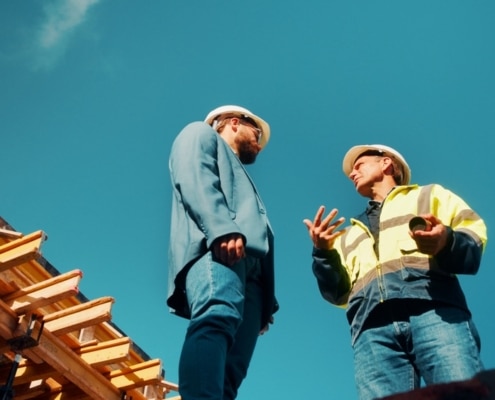 How to Spot a Storm-Chasing Roofing Scam in South Florida – two roofing professionals discussing a construction project beside a residential roof structure.