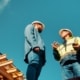 How to Spot a Storm-Chasing Roofing Scam in South Florida – two roofing professionals discussing a construction project beside a residential roof structure.